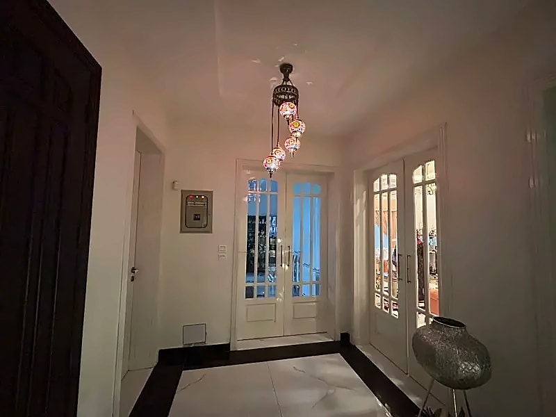 Entrance hall with tiled flooring, hanging lights and glazed doors in the D-12/4 rental house