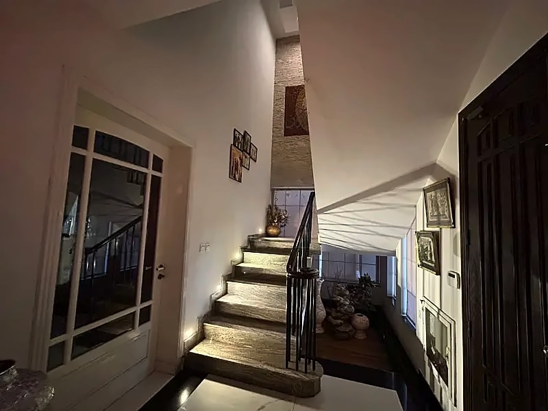 Staircase with illuminated steps and a dark handrail inside the D-12/4 rental house